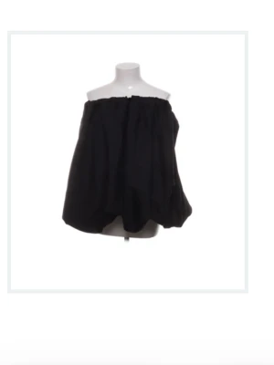 Svart offshoulder tubtopp - Trendig svart offshoulder tubtopp med lös passform och ballongliknande siluett. Toppen är axelbandslös och har en enkel, stilren design som passar perfekt till många olika looks.