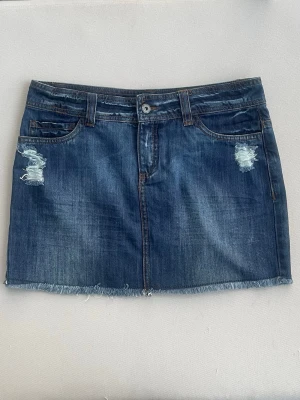 Kort jeanskjol ONLY - Super fin lågmidjad mörkblå jeans kjol från populära märket ONLY. Utmärkt skick. Snygga slitningar till detaljer.  Mått:  Midjemått: 40cm  Längd: 34cm  