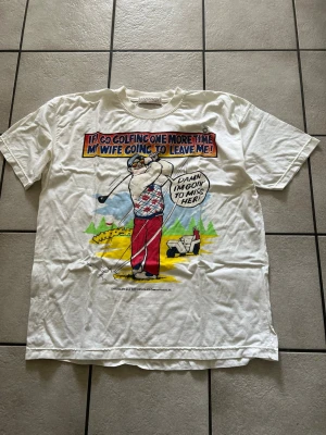 Vit t-shirt med golfmotiv och tryck storlek XXL bomull  - Rolig vit t-shirt från Good On You med färgglatt golfmotiv och texttryck på framsidan. T-shirten har rund hals och korta ärmar. Perfekt för dig som gillar humoristiska plagg och vill sticka ut lite extra.