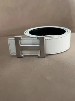 Vitt skärp med silver H-spänne - Snyggt vitt skärp från H&M med ett stort H-format spänne i silverfärg. Bältet har en stilren design och är gjort i skinn. Perfekt accessoar för att lyfta vilken outfit som helst.
