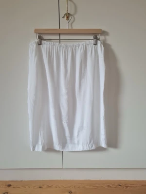 Vit underkjol med resårmidja  - Underkjol,   Saknar ettiket om storlek , känns som str L Totalt längd  67 cm Saknar ettiket om material men känns som viskos.