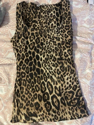 Leopardmönstrad ärmlös linnetopp OBS insydd så den är xxs - Snygg ärmlös topp med leopardmönster i bruna och svarta toner. Perfekt för dig som vill sticka ut och addera lite edge till din outfit. Mjuk och stretchig känsla, passar till många olika stilar.