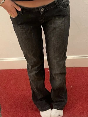 Svarta bootcut jeans med brodyr - Säljer ett par svarta bootcut jeans med snygg kontrastsöm och broderade detaljer på bakfickorna. Jeansen har låg midja och klassisk femficksmodell. Storlek 44 (tror att det är italiensk storlek), passar som 36/38! 🥰