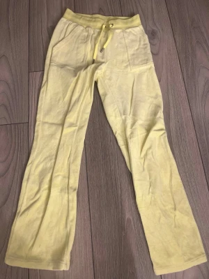 Gula mjukisbyxor med dragsko - Snygga ljusgula mjukisbyxor med raka ben och bred resår i midjan från Juicy Couture. Perfekta för chill dagar eller när du vill vara extra bekväm. Om tröja önskas så går det att köpa till.