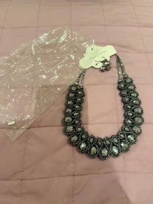 Statementhalsband med silverpärlor - Snyggt statementhalsband med stora, droppformade silverfärgade pärlor och dubbla rader. Halsbandet har en glittrig och elegant look som verkligen drar blickarna till sig. Perfekt för dig som vill sticka ut och addera lite extra bling till din outfit.