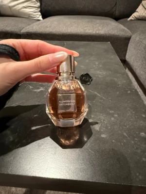 Flowerbomb parfym från Viktor & Rolf - Flowerbomb parfym från Viktor & Rolf i en elegant, multifacetterad glasflaska med ljusrosa doftvätska och silverfärgad kork. Flaskan har en svart dekordetalj vid halsen och en modern, lyxig känsla. Helt nya då jag fick två stycken. 