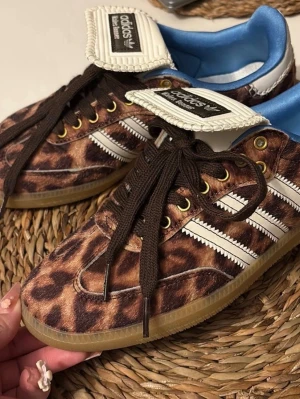Adidas sneakers med leopardmönster - Unika Adidas sneakers med leopardmönster, bruna skosnören och klassiska vita stripes på sidan. Skorna har gummisula, guldfärgade öljetter och blå insida. Tungan är vit med svart Adidas-logga. Perfekta för dig som vill sticka ut med din stil. This model rund small size , originally is 39 but fits for 38 or 381/2