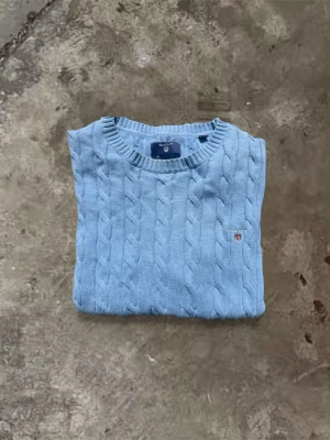 Gant Cableknit - Säljer en ljusblå kabelstickad tröja i storlek M från Gant. Tröjan är smått använd men i bra/mycket bra skick. Nypris ca 1500kr. Tröjan tvättas innan frakt.