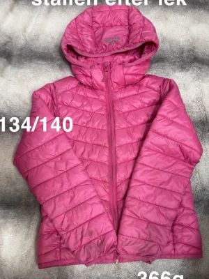 Rosa jacka med huva - Snygg rosa jacka med huva och dragkedja framtill. Jackan har quiltad design. Jackan har en modern passform som funkar till det mesta.🌸Mörka fläckar från lek. Storlek 134/140