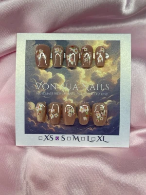 SakuraBlossom (S);Short Ballerina - Handgjorda press-on naglar i nuderosa cateye med vita och rosa körsbärsblommor samt gröna blad. Naglarna har en kort, ballerina form och detaljer. Perfekta för dig som vill ha en söt och unik look. S: 15 mm, 11,5 mm, 12 mm, 11 mm, 9 mm 