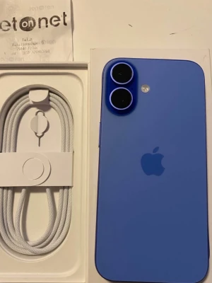 Blå Apple iPhone med dubbla kameror - Säljer en snygg blå iPhone 16. Telefonen har en stilren, platt design i glas och aluminium utan täcken på några skador eller repor. Medföljer gör en vit USB-C till Lightning-kabel och SIM-kortsverktyg. Mobilen har 100% batteri hälsa och används fåtalt dagar. Säljer då den bara ligger hemma.