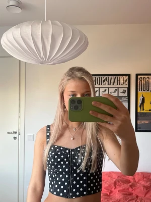 Svart prickig korsettopp med dragkedja - Skitsnygg och cool svart prickig korsettopp med dragkedja och axelband🖤🤍🖤🤍 Perfekt för fest! Storlek och märke står inte men det är typ en XS/S