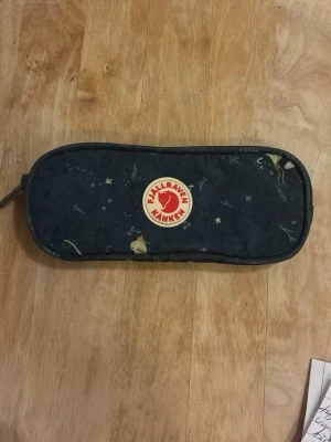 Mörkblå Kånken pennfack med mönster - Min kropps olja i doft av argan olja läkte i den, den är inte kladdig men det kan bli lite strävt på finger topparna. Annars är det inga defekter, köpte den i somras och använd 3 ggr.