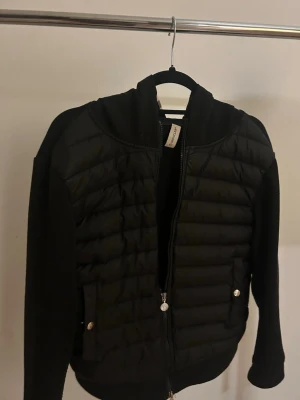 Svart pufferjacka från Moncler -  Hej, säljer denna Moncler cardigan( den är 1:1kopia) den är ju bra skick förutom att lappen hänger löst på ena sidan där bak. Det är storlek m men den funkar nog bra för s ochså