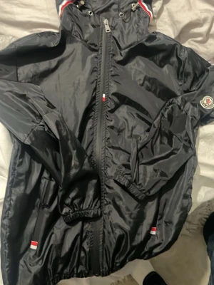Svart vindjacka  - Svart moncler vind jacka. Väldigt tunn och skön att ha till sommaren. Passar någon som är runt 170-180 