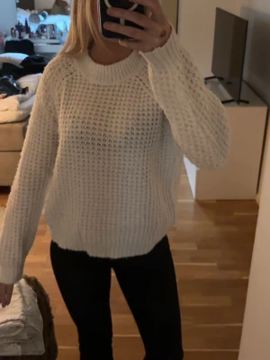 Vit chunky stickad tröja - Säljer en vit stickad tröja med grov struktur och rund hals. Den har långa ärmar ribbade muddar vid ärmslut och nederkant. 