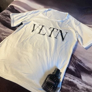 Vit VLTN t-shirt från - Snygg vit t-shirt från Valentino med stor svart VLTN-logga på bröstet. Klassisk rund halsringning pad och korta ärmar. Perfekt för dig som gillar stilrena och trendiga plagg med exklusiv känsla.