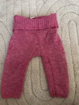 Rosa stickade byxor  - Mysiga rosa stickade byxor med bred ribbad midja som kan vikas ner. Tillverkade i mjukt material som känns skönt mot huden. Perfekta för en avslappnad och bekväm stil. Passar till många olika outfits och är superenkla att matcha.