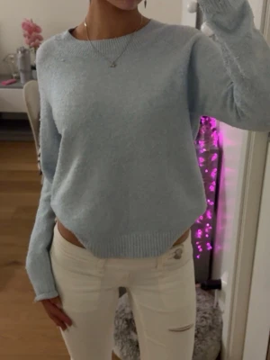 Ljusblå stickad tröja Vero Moda - Mysig ljusblå stickad tröja från Vero Moda med rund halsringning och ribbade muddar vid ärmslut. 