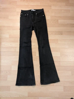 Svarta utsvängda jeans från 157 stl. M - Snygga svarta jeans från 157 med utsvängda ben. Jeansen har hög midja och dragkedja framtill. Stl. M