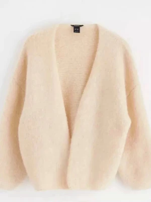 Beige fluffig kofta från H&M - Mysig beige kofta från H&M med öppen front och breda ärmar. Tillverkad i ett fluffigt material som ger en avslappnad och trendig look. Perfekt att slänga över en t-shirt eller topp för extra värme och stil.