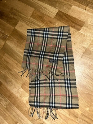 Klassisk rutig halsduk från Burberry - Säljer 100% cashmere köpte för 5000kr på amerikansk online Auktion! Har använt några gånger på resturang bara. Bra skick 