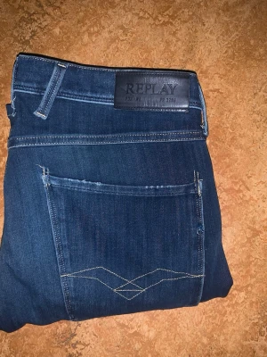 Mörkblå jeans från Replay - Snygga mörkblå jeans från Replay med klassisk femficksmodell och kontrastsömmar. Jeansen har en läderpatch med Replay-logga bak i midjan och raka ben. Tillverkade i mjukt denimtyg som ger en skön passform.