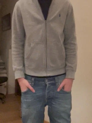 Grå Ralph Lauren zip  - Jag säljer denna gråa Ralph Lauren zippen med luva. Den är i 8/10 skick och är frånbörjan köpt från kids brand store för ~1200. Den funkar perfekt som tjocktröjan nu på våren eller en sommarkväll! Jag är 172 och den är på gränsen till för liten på mig. Så jag skulle säga att den passar som bäst på folk mellan 164-170. Jeansen är också till salu på min profil. Priset kan diskuteras och det är bara att skriva om ni har frågor! 