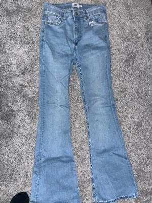 Ljusblå bootcut jeans från 157 - Säljer ett par ljusblå bootcut jeans från 157 med klassisk femficksdesign och normal passform. Jeansen har utsvängda ben och är tillverkade i mjuk bomull. Perfekta för dig som gillar retrostil och vill ha ett par snygga jeans. Passar både som Xs och S