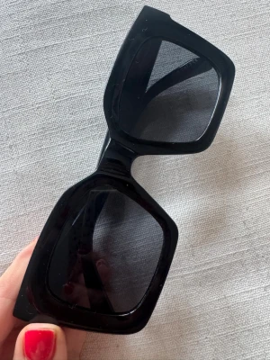 Svarta fyrkantiga solglasögon - Stilrena solglasögon med breda, fyrkantiga bågar. Glasen är mörka och ger en cool, modern vibe. Perfekta för dig som vill sticka ut med en trendig accessoar till sommaren. Har bundlerabatt vid köp av fler varor🥰