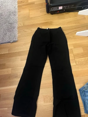 Svarta vida byxor - Säljer ett par svarta byxor med breda ben och enkel design. Byxorna har en klassisk look och passar perfekt till en avslappnad eller trendig outfit. Materialet känns mjukt och bekvämt, och modellen är loose fit för extra komfort.