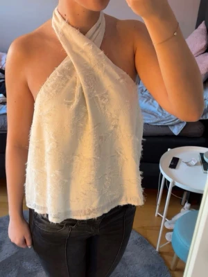 Vit omlott halterneck topp - Säljer en vit omlott topp med halterneck och lätt struktur i tyget. Köpt second hand och står inget märke men misstänker att den kommer från SHEIN, där av priset😇