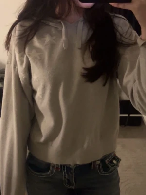 Ljusgrå hoodie med stjärnor - Ljusgrå hoodie med huva och dragsko, dekorerad med diskreta stjärnor på ena axeln. Hoodien har en avslappnad passform och ribbade muddar vid ärmslut och midja. Perfekt för en chill och bekväm stil.