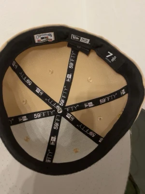 Beige New Era 59FIFTY White Sox keps - Snygg beige keps från New Era 59FIFTY med mörkgrön skärm och broderad White Sox-logga framtill. Klassisk flatbrim-modell med Cooperstown Collection-märke på insidan. Perfekt för dig som vill ha en stilren och sportig look.