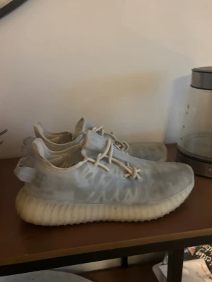 Yeezy Boost 350 V2 Mono ice sneakers - Säljer ett par Yeezy Boost 350 V2 sneakers i ljusblått(dåligt ljus på bilden)  med semi-transparent mesh och vita detaljer. Skorna har den ikoniska ribbade sulan och elastiska snören för en clean och modern look. Perfekta för dig som gillar streetwear och vill sticka ut.