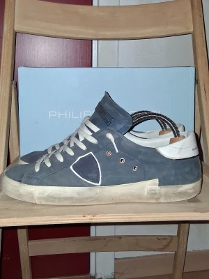 Blå sneakers från Philippe Model - Storlek 42. Skorna har använts så defekter förekommer, men inget som stör utseenedet. Limmet på sulan har lossnat lite, lite i kanten men absoult inget som man tänker på. Se sista bilden. Priset är inte hugget i sten så tveka inte att höra av er!