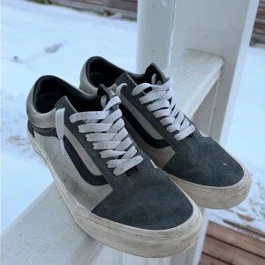 Vans Old Skool sneakers - Klassiska Vans Old Skool sneakers i grått mocka och canvas. Skorna har vit sula, vita skosnören och den ikoniska svarta sidostripen. Låg modell som passar perfekt till streetwear och casual outfits.
