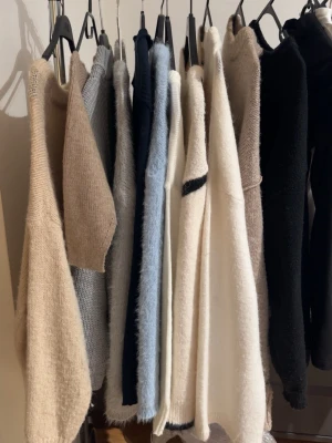 Stickade tröjor i neutrala färger - Flera stickade tröjor i beige, vitt, svart, grått och ljusblått. Tröjorna har lång ärm och är gjorda i mjukt, fluffigt material med avslappnad passform. Perfekta för lager på lager och en stilren look.