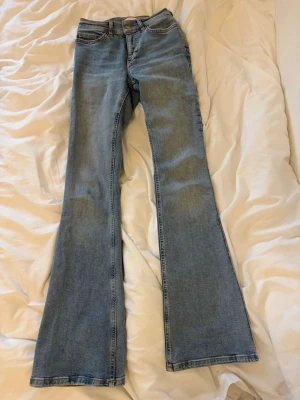 Ljusblå bootcut jeans Gina tricot - Säljer ett par ljusblå bootcut jeans med klassisk femficksdesign och hög midja. Jeansen har en snygg utsvängd passform och är tillverkade i denim. Perfekta för dig som gillar retrostil och vill ha ett par jeans som sticker ut.