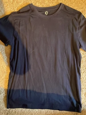 Mörkblå t-shirt från C - En enkel och stilren mörkblå t-shirt från C med rund halsringning och korta ärmar. Tillverkad i mjukt bomullsmaterial som känns skönt mot huden. Perfekt basplagg att matcha med olika outfits.