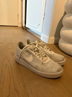 Nike Air Force 1 vita sneakers - Snygga vita Nike Air Force 1 sneakers med klassisk låg profil och stickad mesh överdel. Skorna har vita snören, tydlig Nike-logga på sidan och bak samt en robust sula med Air-dämpning. Perfekt för dig som gillar stilrena och ikoniska sneakers. OBS! PRIS KAN DISKUTERAS