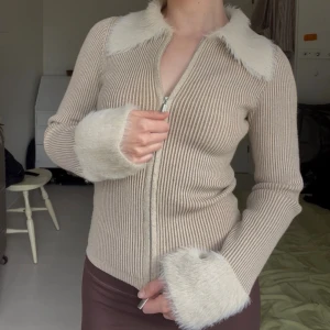 Ribbad slimmad kofta - Ribbad långärmad kofta med fluffiga muddar och krage. Dragkedja som går åt båda hållen 