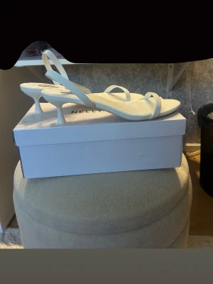 Vita pumps med smala remmar från Nelly - Snygga vita pumps från Nelly med smala remmar och öppen tå. Endast testade, så i nyskick!💗