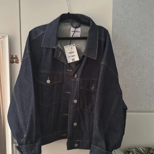 Mörkblå jeansjacka från Bershka - Snygg mörkblå jeansjacka från Bershka. Helt ny endast testad, prislappen finns med. Pris kan diskuteras. Har inga bilder där jag har på mig den. Köpte för stor storlek därav säljs den.