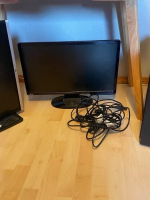 Komplett stationär dator med skärm - Säljer en svart stationär dator från Komplett med tillhörande skärm och kablar. Datorn har en klassisk rektangulär form och frontpanel med USB-portar och DVD-läsare. Skärmen är svart och har en stabil fot. Perfekt för gaming eller studier.