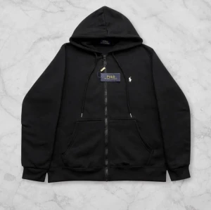 Polo Ralph Lauren zip  - Svart Polo Ralph Lauren Hoodie  Lyxig svart hoodie med tidlös och exklusiv känsla 💎 Mjukt premium-material som ger både komfort och stil ✨ Minimalistisk design som funkar till allt – alltid rätt 🖤 Plagget är i toppskick och redo att användas 👌  🔹 Märke: Polo Ralph Lauren 🔹 Färg: Svart 🔹 Skick: Mycket fint 🔹 Passform: Klassisk  📦 Snabb leverans 💎✨