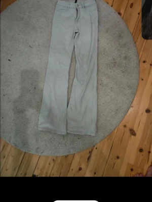Ljusgrå bootcut jeans - Säljer ett par ljusgrå jeans med bootcut passform och klassisk femficksdesign. Jeansen har knapp- och dragkedjestängning samt raka ben som blir bredare nedtill. Perfekta för dig som gillar en avslappnad och trendig stil.
