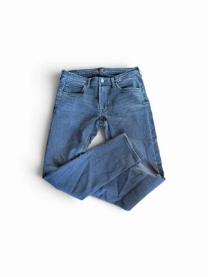 Mörkblå jeans från Lee - Snygga mörkblå jeans från Lee med klassisk femficksmodell och raka ben. Jeansen har Lee-logga på bakfickan och bak i midjan. Tillverkade i mjukt denimtyg som ger en skön passform och stilren look.