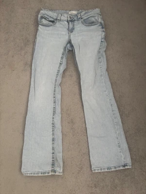 Ljusblå bootcut jeans från Gina Tricot - Ljusblå tvätt, lågmidjade jeans från Gina Tricot. Lite slitnad vit benkanten.