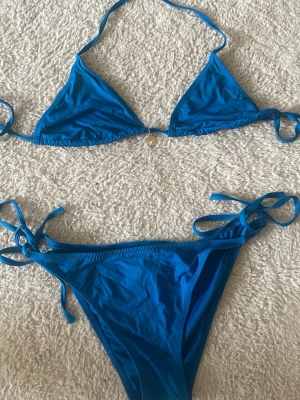 Mörkblå bikini med guldig snäcka  - Mörkblå med en guldig snäcka som ger den en fin detalj, perfekt på stranden. 